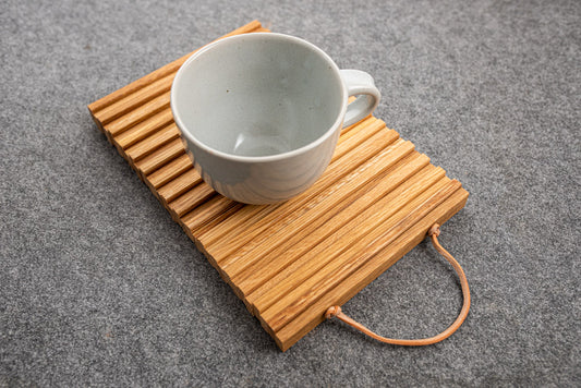Untersetzer aus Eichenholz mit Ledergriff und Tasse.